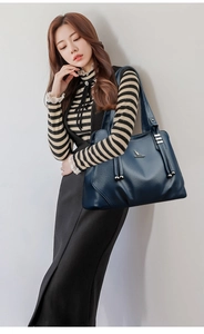 Detail of dark blue lychee grain leather tote bag with gold logo and decorative drawstrings