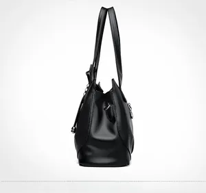 Side view of black lychee grain leather tote bag with metal D-rings and durable stitching