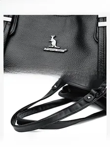 Macro view of black lychee texture leather handbag with silver kangaroo logo and stitching