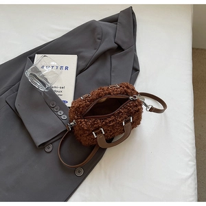 Détail d'un mini sac cylindrique en polaire marron avec poignée en cuir sur blazer