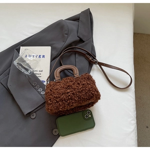 Vue détaillée du sac boîte en peluche marron avec bandoulière sur un blazer chic