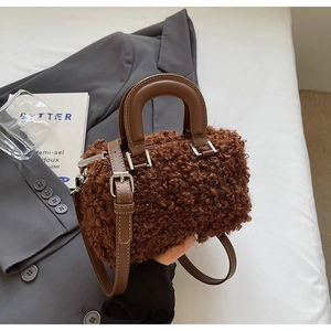 Detailed close-up of brown faux shearling bag with leather handles and silver hardware
