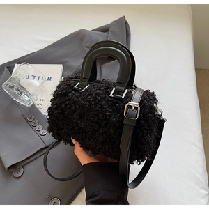 Detail of black faux fur cylindrical bag with leather handle and silver metal buckle
