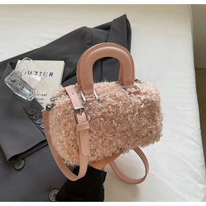 Détail d'un sac cylindrique en peluche rose montrant sa texture douce et sa boucle en argent