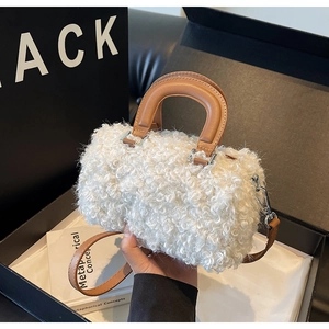Détail du sac baril en peluche blanche avec poignées en cuir marron et boucles argent