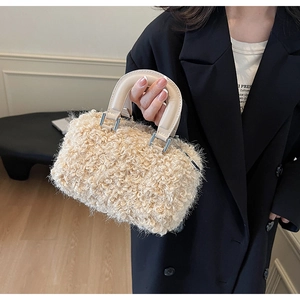 Détail d'un mini sac en peluche crème avec poignée en cuir et anneaux métalliques