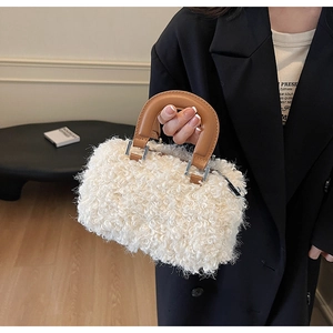 Détail de la texture pelucheuse blanche et de la poignée en cuir marron du sac fourre-tout