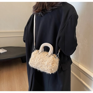 Détail du sac cylindrique en peluche crème montrant la texture bouclée et la bandoulière