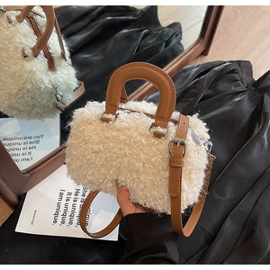 Close-up of white fleece cylinder bag with brown faux leather straps and silver buckles