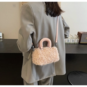 Mini sac boîte en fausse fourrure rose porté en bandoulière sur un blazer gris