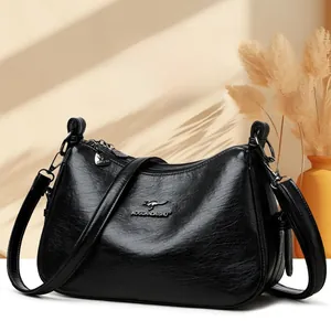 Detail of black pebbled leather texture with gold metal kangaroo logo on tote bag