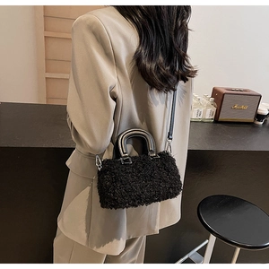 Detail of black faux shearling bag with silver hardware and smooth leather handles