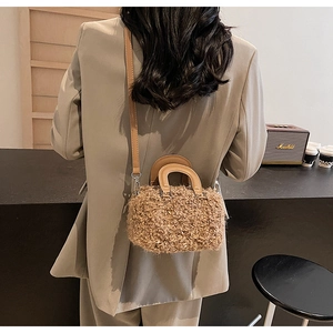 Detail of plush crossbody bag with brown faux fur texture and leather strap style