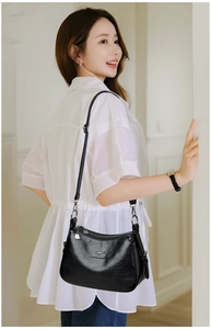 Detail of black lychee leather crossbody bag with golden kangaroo logo and adjustable strap