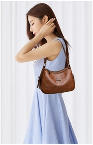 Close-up of vintage brown leather shoulder bag with fine texture and silver logo detail