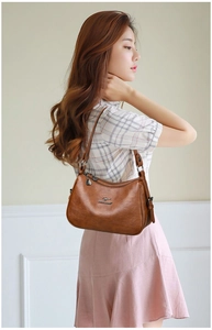 Detail shot of brown leather shoulder bag featuring kangaroo logo and metallic zipper