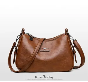 Detailed view of brown leather crossbody bag with lychee texture and dual zippers