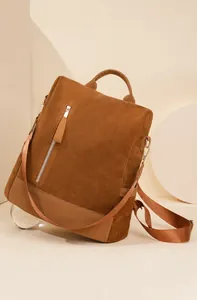 Detailaufnahme eines karamellbraunen Lederrucksacks mit goldenen Metallreißverschlüssen