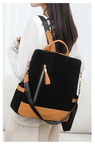 Seitenansicht eines schwarzen Wildleder-Rucksacks mit braunen Lederdetails und Gold