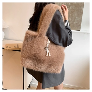 Detail of plush brown faux fur tote bag with white cotton tassels and metallic buckle
