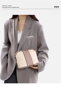 Dettaglio di una borsa a tracolla bicolore beige e taupe con finiture in oro lucido