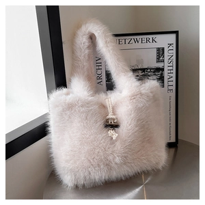 Detail of fluffy cream faux fur tote bag with decorative rope knot on a stylish table