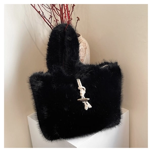 Close-up of black faux fur tote bag featuring a decorative toggle closure on a white pedestal