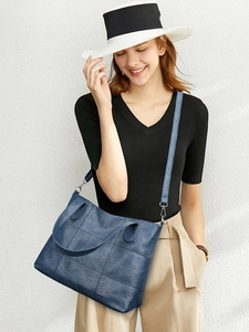 Detail of blue textured leather tote bag featuring contrast stitching and leather handle