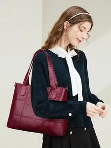 Detailed side view of deep red quilted tote bag shown on model with wide shoulder straps