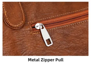 Detail of silver hardware zipper pull on brown lychee texture leather shoulder bag