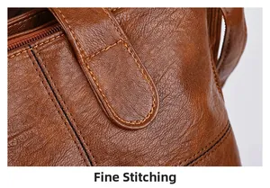 Macro shot of fine stitching on the handle connector of a brown leather tote bag