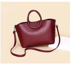 Close-up of burgundy lychee leather tote bag featuring woven handles and adjustable strap