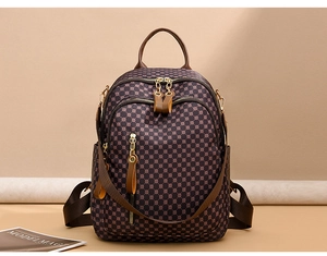 Detailed front view of vintage patterned backpack with brown leather handles and pockets