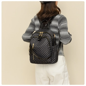 Macro shot of geometric floral print backpack with gold zippers worn by model