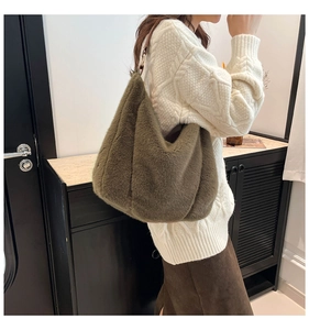 Detail of soft faux fur shoulder bag in dark olive green featuring a brown leather handle