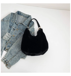Detail of black plush hobo bag with gold ring hardware and leather strap on denim fabric