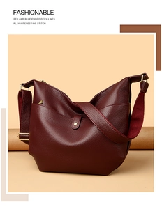 Detail of dark burgundy pebble leather hobo bag with a wide fabric strap and gold hardware