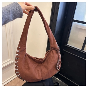 Detail of silver rivets on brown suede crescent hobo bag with a natural matte finish