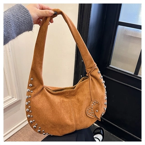 Detail view of brown suede hobo bag featuring silver rivets and a heart-shaped charm