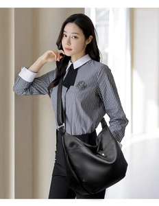 Close-up of black litchi grain leather hobo bag with gold buckle on a crossbody strap