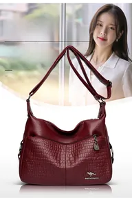 Detail of burgundy PU leather shoulder bag with embossed crocodile texture and metal logo
