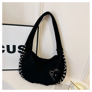 Detail of black suede crescent bag featuring silver studs and a heart-shaped pendant charm