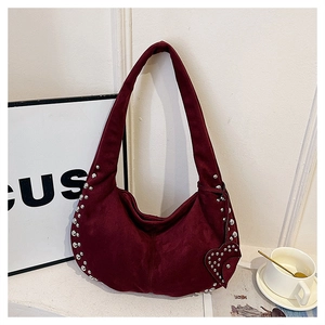 Detail view of burgundy faux suede crescent bag with silver studs and heart charm