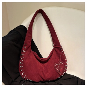 Close-up of wine red suede hobo bag with silver rivet details on a white chair