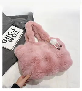 Detail of pink faux fur bucket bag featuring a soft texture and white fuzzy pom-pom charm