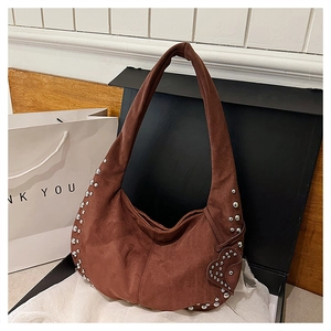 Detailed view of brown suede crescent bag with silver rivets and heart charm in a gift box