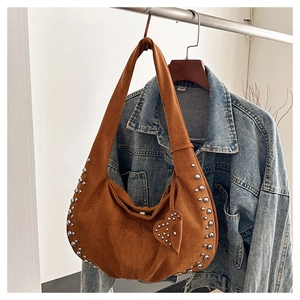 Detail of suede crescent bag featuring silver rivets and heart pendant charm