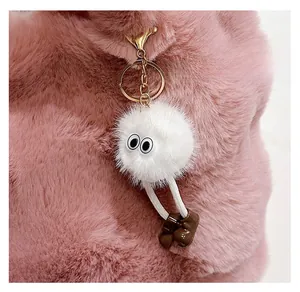 Close-up of a cute white plush ball charm with big eyes and a golden keychain on a pink bag