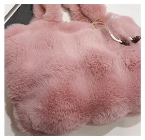 Close-up of pink faux fur bucket bag featuring a soft white pompom and metal ring detail