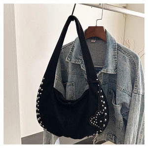 Detail of black crescent hobo bag featuring silver rivets and a heart charm pendant
